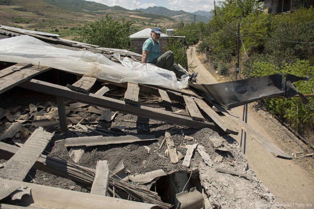 A villager works to cover his damaged roof in Aygepar before the rains. Photo credit: Hetq